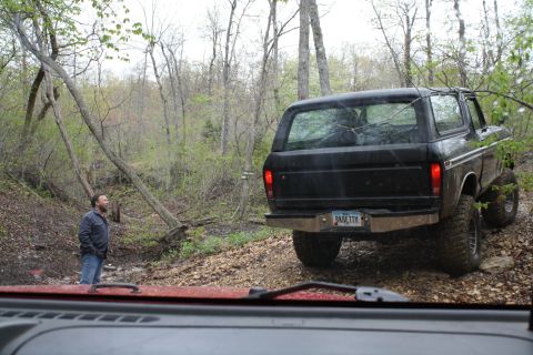 1979 Ford Bronco - A black 1978 Ford Bronco navigates a wooded trail, seen from the perspective of another vehicle.