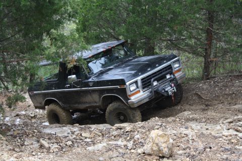 1979 Ford Bronco - This black Ford Bronco is navigating a difficult off-road trail, getting stuck in the mud and rocks.