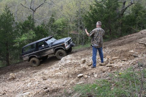 1979 Ford Bronco - A black 1979 Ford Bronco navigates a steep, rocky incline with a person observing.