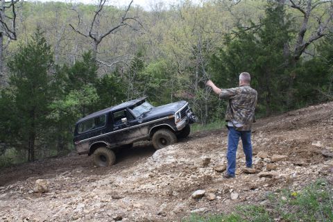1979 Ford Bronco - Ford Bronco navigating challenging off-road terrain with a person observing.