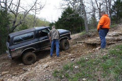 1979 Ford Bronco - A black 1979 Ford Bronco navigates a challenging off-road trail with two men observing.