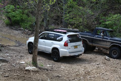 1979 Ford Bronco - A black 1979 Ford Bronco is parked on a dirt trail next to a white Lexus SUV, both appearing to be off-roading.