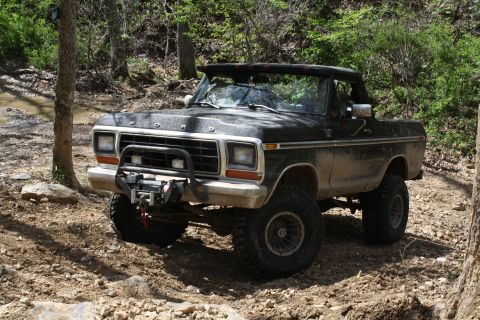 1979 Ford Bronco - This lifted Ford Bronco navigates a muddy, wooded trail with a winch mounted on the front bumper.