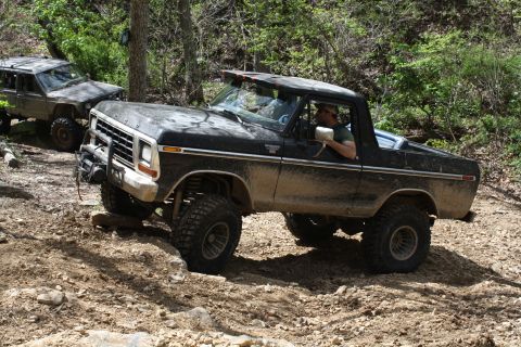 1979 Ford Bronco - A black 1978 Ford Bronco navigates a rocky off-road trail with another vehicle visible behind it.