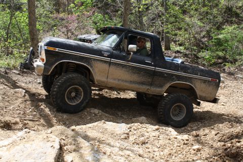 1979 Ford Bronco - This lifted Ford Bronco navigates a rocky, off-road trail with trees in the background.