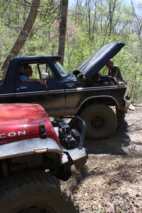 1979 Ford Bronco - Two off-road vehicles are parked on a dirt trail, one with its hood up for inspection.
