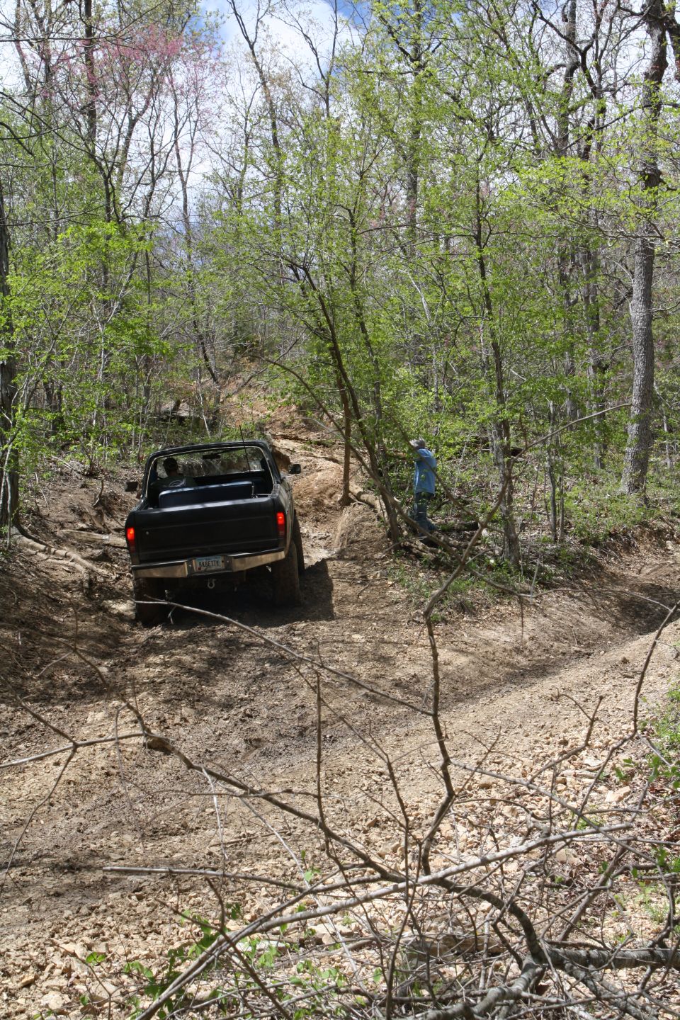 Black 1979 Ford Bronco driving on a wooded dirt trail