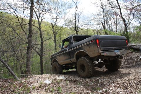 1979 Ford Bronco - This lifted Ford Bronco is navigating a rocky trail in a wooded area.
