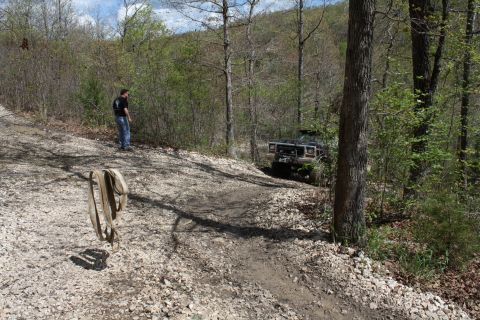 1979 Ford Bronco - A black off-road SUV navigates a challenging dirt trail surrounded by trees.