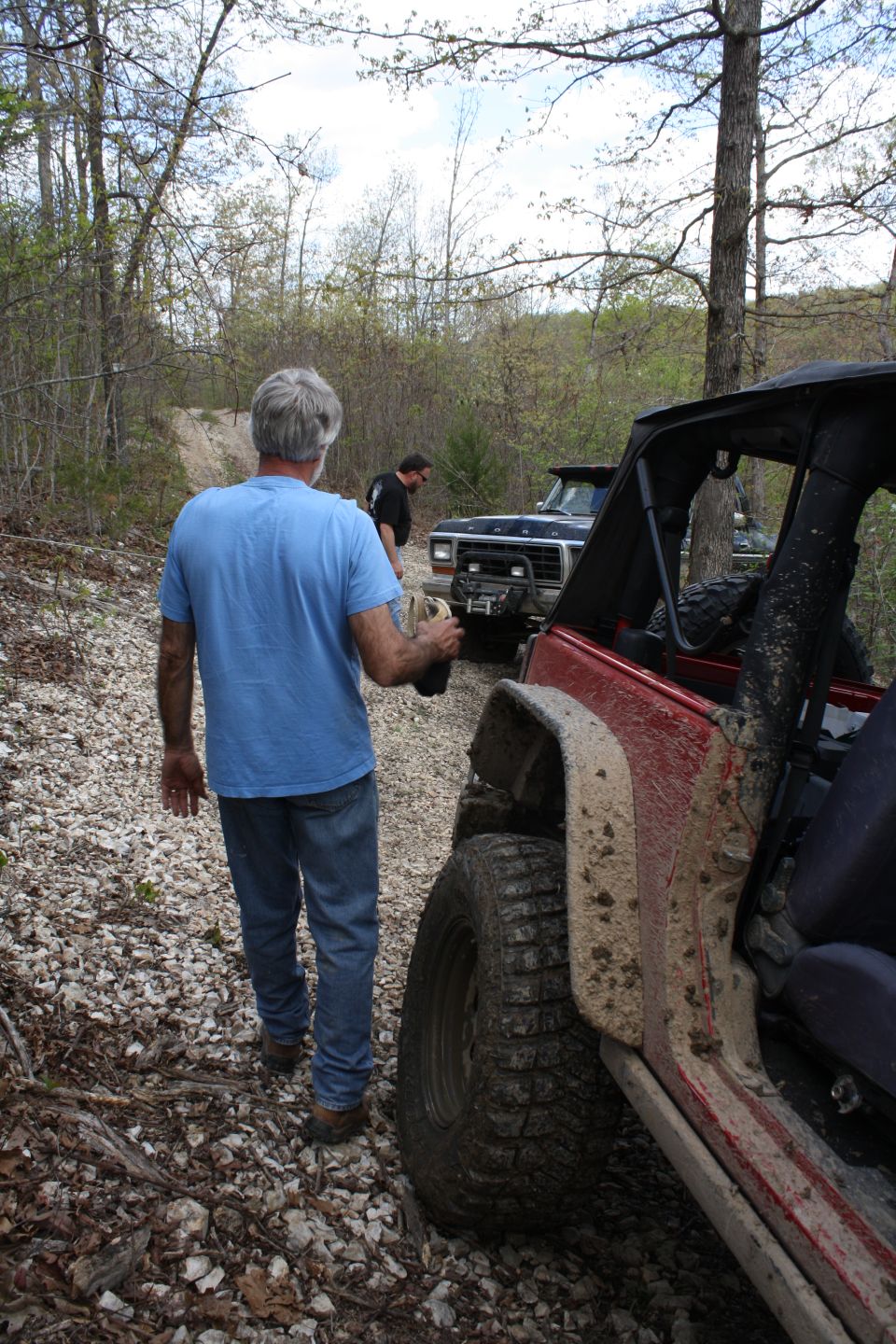 1979 Ford Bronco front grille and bumper, muddy, off-road tires, parked on gravel path