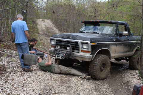 1979 Ford Bronco - A black 1978 Ford Bronco is being worked on by three people on a dirt road.