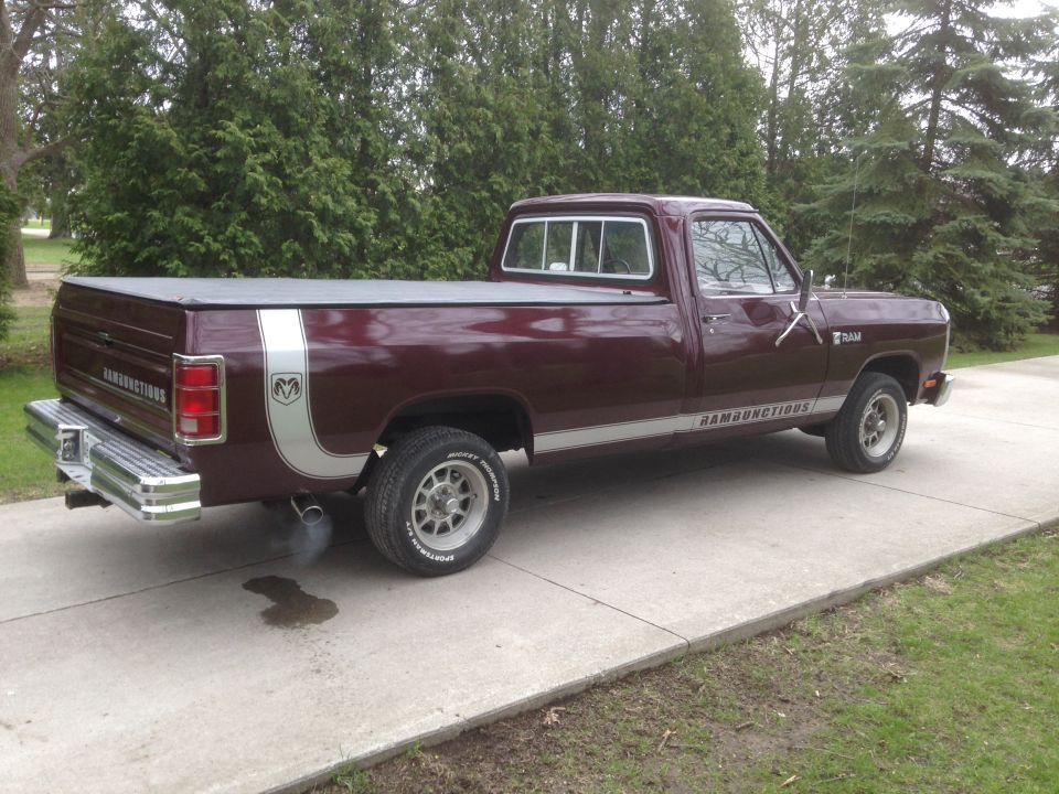 Maroon Dodge Ram pickup truck with silver stripe and 'RAMBUNCTIOUS' decal. Exhaust smoke visible