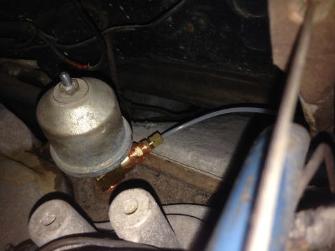 1979 Ford Bronco - Close-up view of a vehicle's undercarriage, focusing on a vacuum canister and brake line connection.