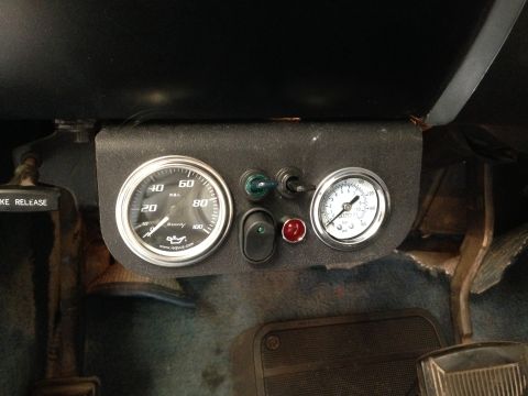 1979 Ford Bronco - Aftermarket gauges and switches are mounted on the dashboard, with a brake release lever visible to the left.