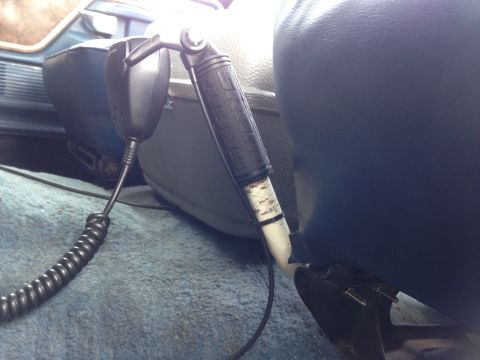 1979 Ford Bronco - Close-up of a CB radio microphone mounted inside a vehicle's interior, showing the coiled cord and mounting bracket.