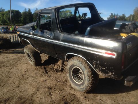 1979 Ford Bronco - This black SUV, likely a 1978 model, is stuck in the mud with its driver's door ajar.
