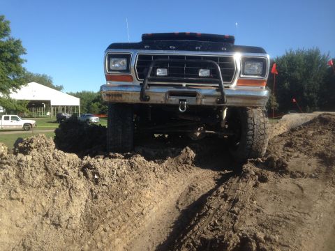 1979 Ford Bronco - A lifted black Ford F-Series truck navigates a dirt obstacle course at an outdoor event. The "SUPER MOTORS" watermark is visible at the bot…