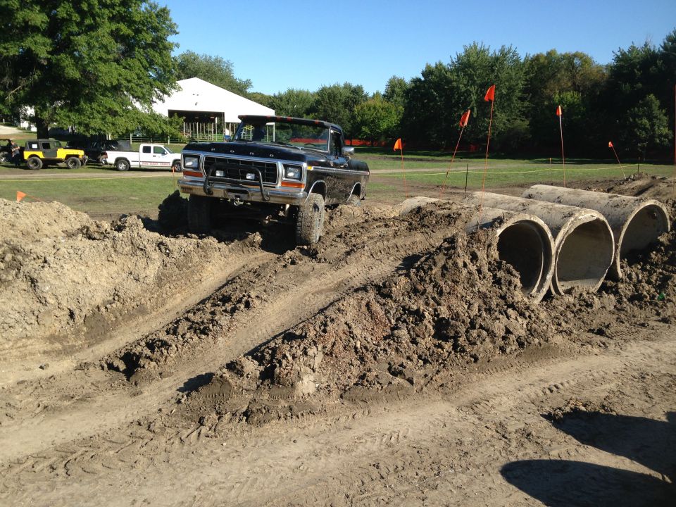 Black 1979 Ford F-150 pickup truck going over an obstacle course with concrete pipes