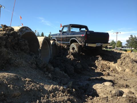 1979 Ford Bronco - A black 1979 Ford Bronco navigates an off-road obstacle course with dirt and concrete pipes.