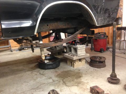 1979 Ford Bronco - The rear axle and leaf spring suspension components are visible, removed from a black vehicle undergoing maintenance.