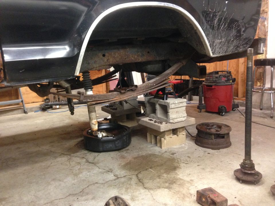 Rear axle and leaf springs removed from a black vehicle, supported by blocks