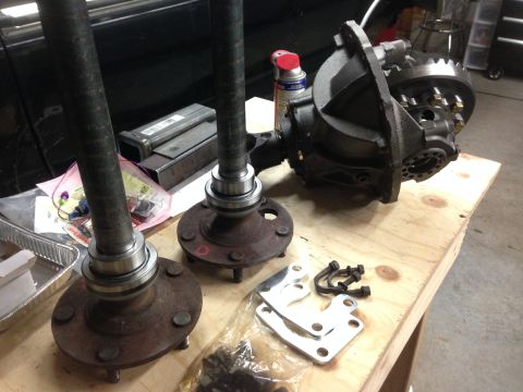 1979 Ford Bronco - Differential and axle shafts laid out on a workbench, likely for repair or replacement.