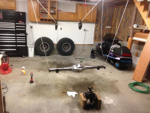 1979 Ford Bronco - Garage scene with a hanging rear axle assembly, large tires, and a snowmobile.