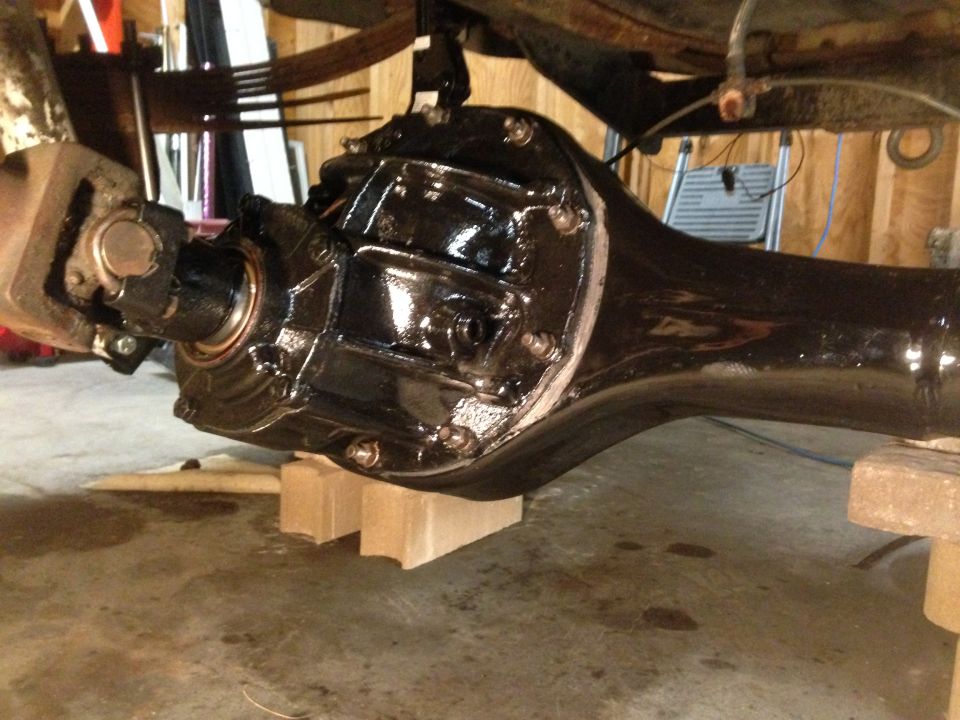 Black rear axle assembly with driveshaft U-joint, supported by wooden blocks