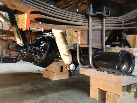 1979 Ford Bronco - Close-up view of a vehicle's rear axle, leaf springs, and shock absorber, likely undergoing maintenance or restoration.