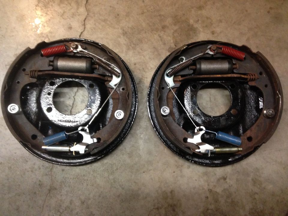 Two drum brake assemblies with shoes, springs, and wheel cylinders. One assembly is on the left, the other on the right