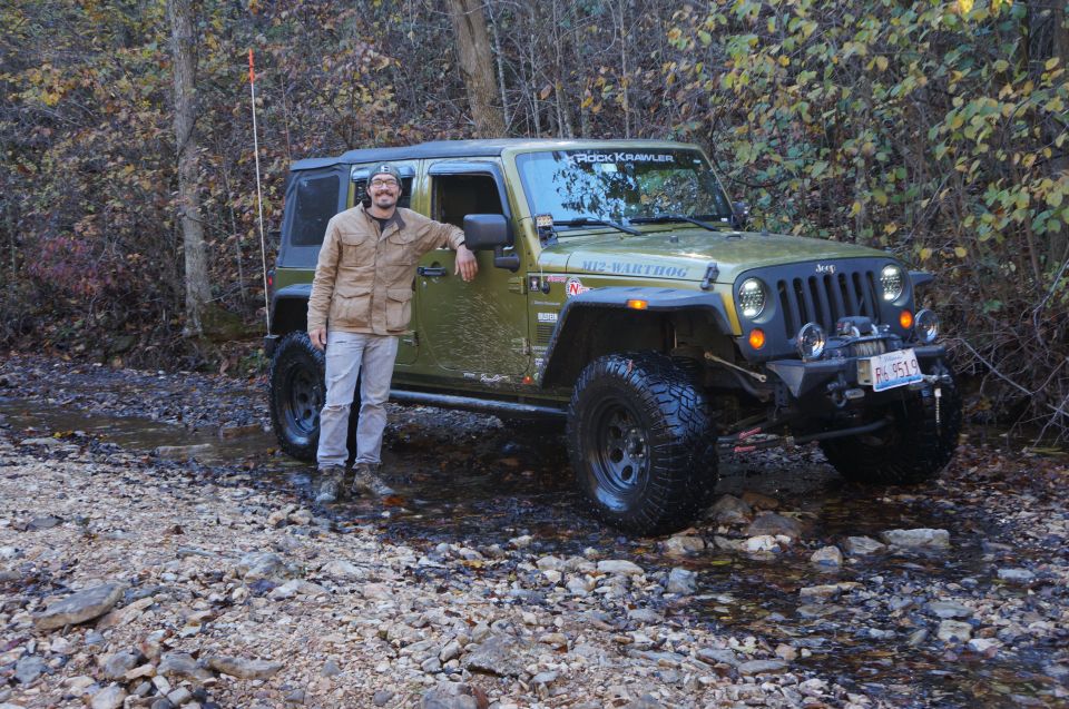 Green Jeep Wrangler with "Rock Krawler" sticker on windshield and "Warthog" decal on fender