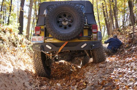 1979 Ford Bronco - A yellow Jeep Wrangler navigates a challenging off-road trail during autumn, with fallen leaves covering the ground.