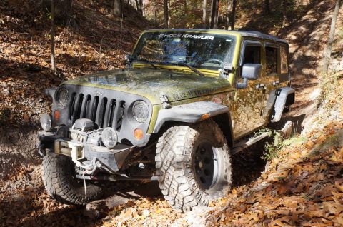 1979 Ford Bronco - A yellow Jeep Wrangler navigates a wooded trail during the fall, with "Rock Krawller" visible on the windshield.