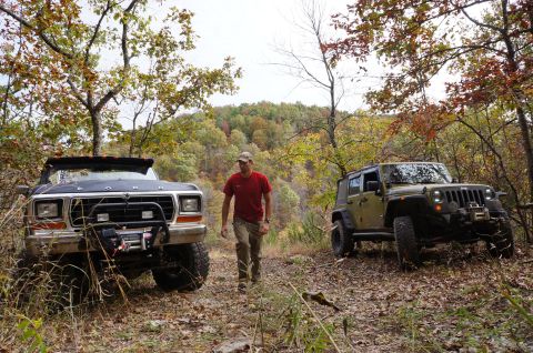 1979 Ford Bronco - Two off-road vehicles, a Ford Bronco and a Jeep Wrangler, are parked on a dirt path during autumn.