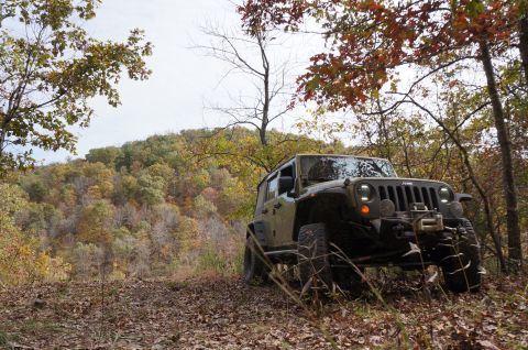 1979 Ford Bronco - A Jeep Wrangler navigates an off-road trail during autumn, with fall foliage visible on the surrounding hills.