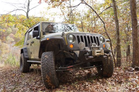 1979 Ford Bronco - A Jeep Wrangler is parked on a wooded trail during the fall season.