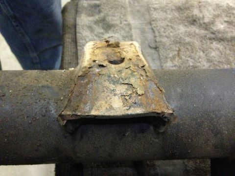 1979 Ford Bronco - A heavily rusted metal bracket is attached to a vehicle's axle, showing significant wear and tear.