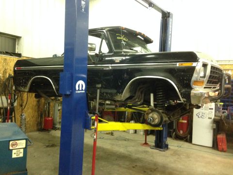 1979 Ford Bronco - Black 1979 Ford Bronco is raised on a hydraulic lift for maintenance in a workshop.