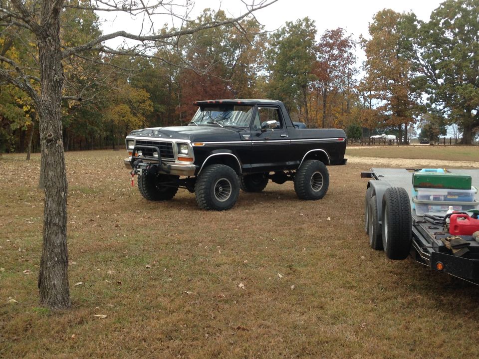 Black lifted Ford Bronco with winch and off-road tires parked next to a trailer