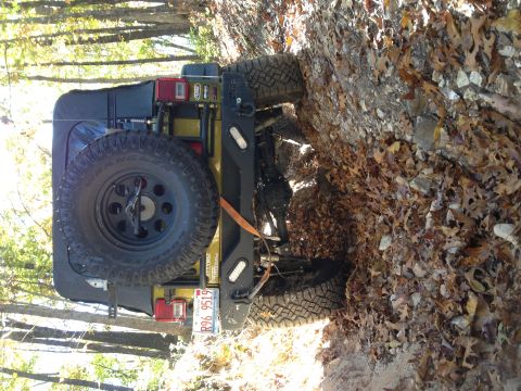 1979 Ford Bronco - A Jeep Wrangler is seen on its side on a wooded trail covered in leaves and rocks.