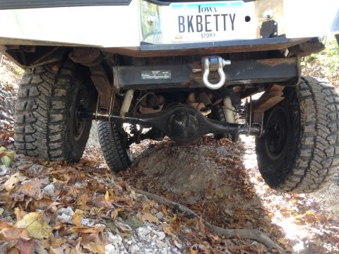 1979 Ford Bronco - Off-road vehicle's rear suspension and axle navigating rough terrain with fallen leaves.