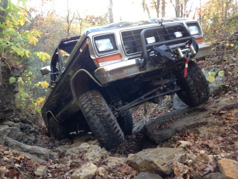 1979 Ford Bronco - Ford Bronco tackling a challenging off-road course with large rocks and uneven terrain.