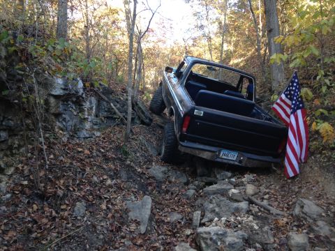 1979 Ford Bronco - Black 1979 Ford Bronco navigates a challenging off-road course, displaying American flags.