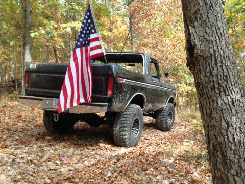 1979 Ford Bronco - A black 1978 Ford Bronco flies an American flag while parked on a leaf-covered trail in the woods.