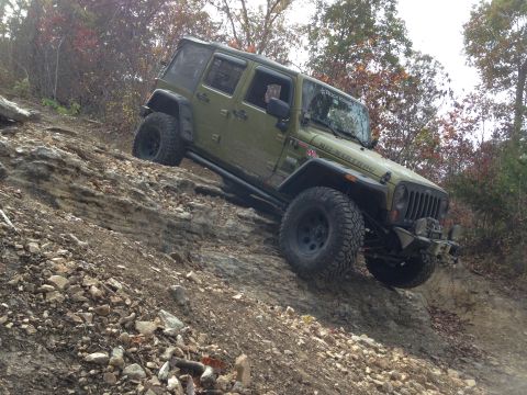 1979 Ford Bronco - A Jeep Wrangler navigates a steep, rocky incline during an off-road excursion.