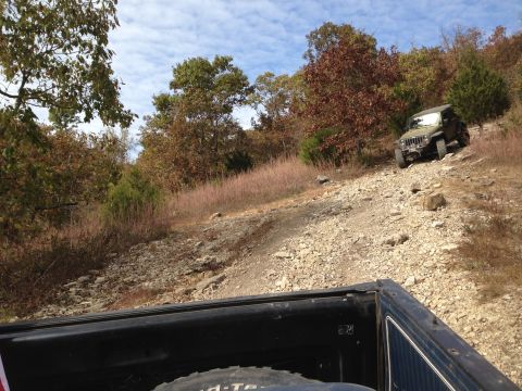 1979 Ford Bronco - A Jeep Wrangler navigates a challenging, rocky incline on an autumn day.