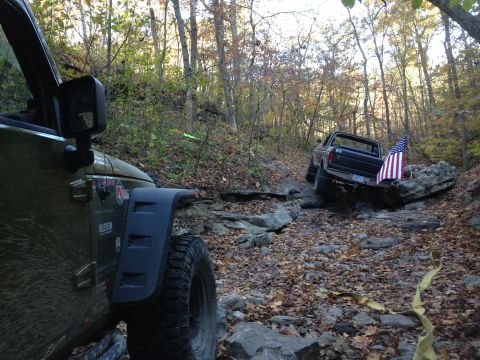1979 Ford Bronco - Two off-road vehicles, a 1979 Ford Bronco and a Jeep, traverse a rocky, wooded trail in autumn.