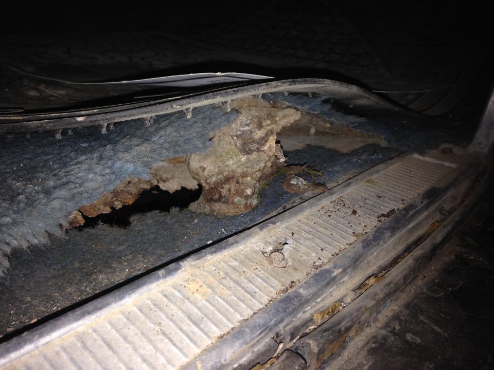 Close-up of severe rust and hole in vehicle floor pan.