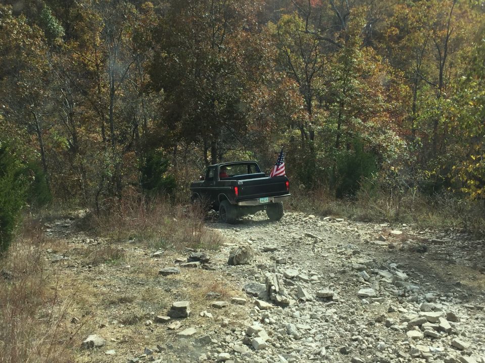 1979 Ford Bronco on a rocky trail with an American flag.