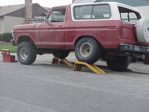 1978 Ford Bronco - This red 1978 Ford Bronco is parked on yellow ramps in a driveway.